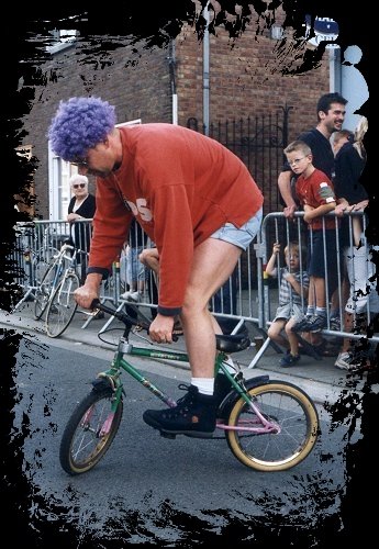 Robert sur-place met klein fietsken en paarse pruik